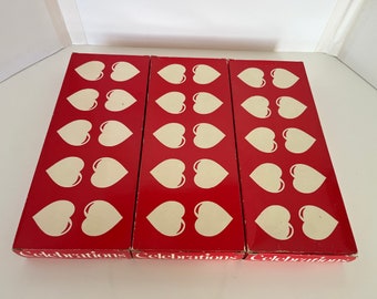 May include: Three red boxes with white hearts printed on them. Each box has the word "Celebrations" printed on the bottom.