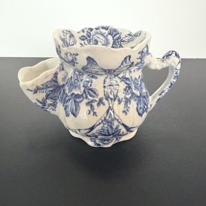 May include: A set of three ceramic mugs with a speckled, cream-colored glaze. Each mug features a different hand-painted design: a sun, a moon, and a star. The mugs have a simple, modern design with a rounded shape.