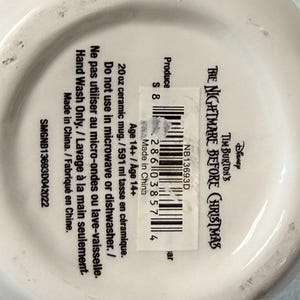 May include: White ceramic mug with the text "Tim Burton's The Nightmare Before Christmas" and a barcode. The mug is 591 ml and should be hand washed only. Made in China.
