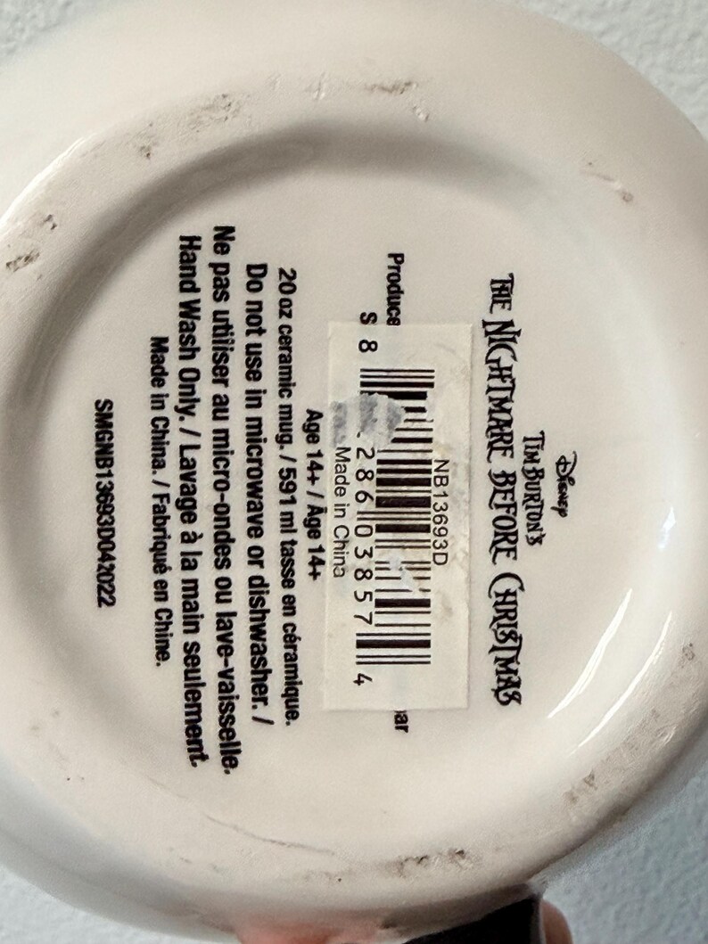 May include: White ceramic mug with the text "Tim Burton's The Nightmare Before Christmas" and a barcode. The mug is 591 ml and should be hand washed only. Made in China.
