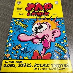 May include: A yellow comic book cover with the title "Zap Comix" in red and black letters. The cover features a cartoon character with a pink face and a large nose. The character is surrounded by stars and the words "Boing!" and "Spring!" in red and black letters. The comic book is labeled "Adults Only!!" and "No. 2".