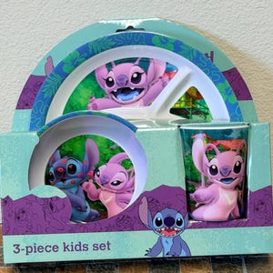 Może przedstawiać: 3-częściowy zestaw dla dzieci z postaciami Stitch i Angel. Zestaw zawiera talerz, miskę i szklankę. Opakowanie jest w kolorze morskim i fioletowym z napisem "3-piece kids set". Talerz i miska mają białe wnętrze z grafiką Stitch i Angel.