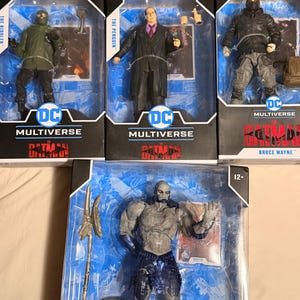 Puede incluir: Cinco figuras de acción de DC Multiverse en su embalaje original. Las figuras incluyen a The Riddler, The Penguin y Bruce Wayne. Las figuras están en varias poses y visten sus trajes característicos. El embalaje presenta el logotipo de DC Multiverse.