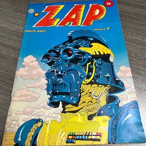 May include: A comic book cover with the title "ZAP" in red letters. The cover features a blue and yellow robot with a large helmet and a gun. The text "ADULTS ONLY" and "NUMBER 7" are also visible on the cover.