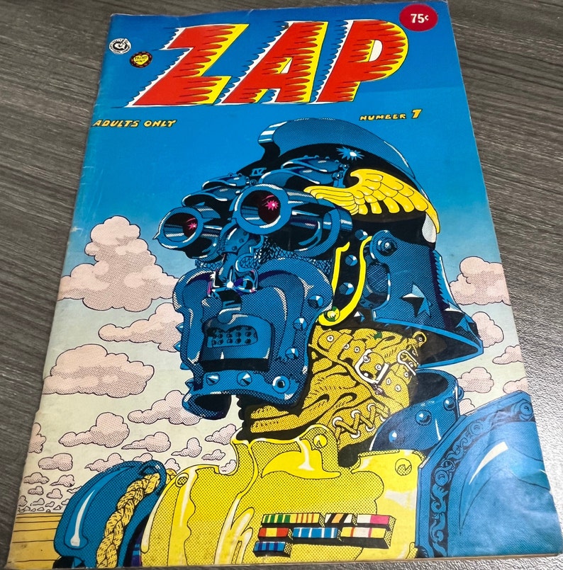May include: A comic book cover with the title "ZAP" in red letters. The cover features a blue and yellow robot with a large helmet and a gun. The text "ADULTS ONLY" and "NUMBER 7" are also visible on the cover.