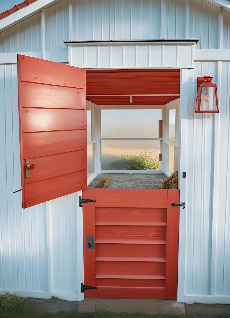 K&ouml;nnte beinhalten: Ein wei&szlig;er Holzstall mit einer roten Holzt&uuml;r und einem kleineren roten Holztor. Der Stall hat ein Fenster mit Blick auf ein Grasfeld.