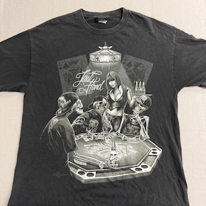 May include: Dark grey t-shirt with a poker-themed graphic. The design depicts skeletons playing poker with a woman, playing cards, and the text "Last Hand". The shirt is a dark colour.