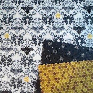 May include: A white fabric with a black damask pattern and bees. The fabric is layered with a black fabric with a white dot pattern and a honeycomb pattern.