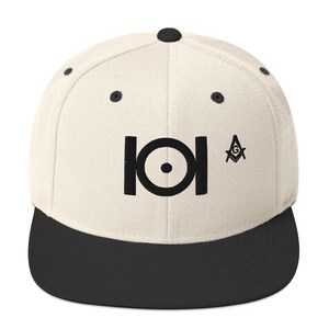 Puede incluir: Una gorra de béisbol de visera plana en blanco y negro con un símbolo en blanco y negro y un símbolo de brújula y cuadrado en blanco y negro. La gorra tiene una visera negra y una corona blanca.