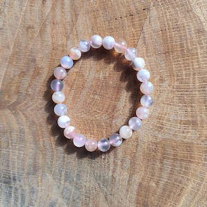 Peut inclure: Un bracelet composé de perles d'agate rose, blanche et grise. Les perles sont rondes et ont une finition lisse et polie.