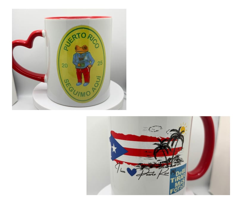 May include: Two white ceramic mugs with red handles. One mug features a green and yellow circular design with a frog wearing a blue shirt and the text "Puerto Rico 20 Seguimo Aqui 25". The other mug features a red, white, and blue Puerto Rican flag with palm trees and the text "I love Puerto Rico Debi Tira Mas Fotos".