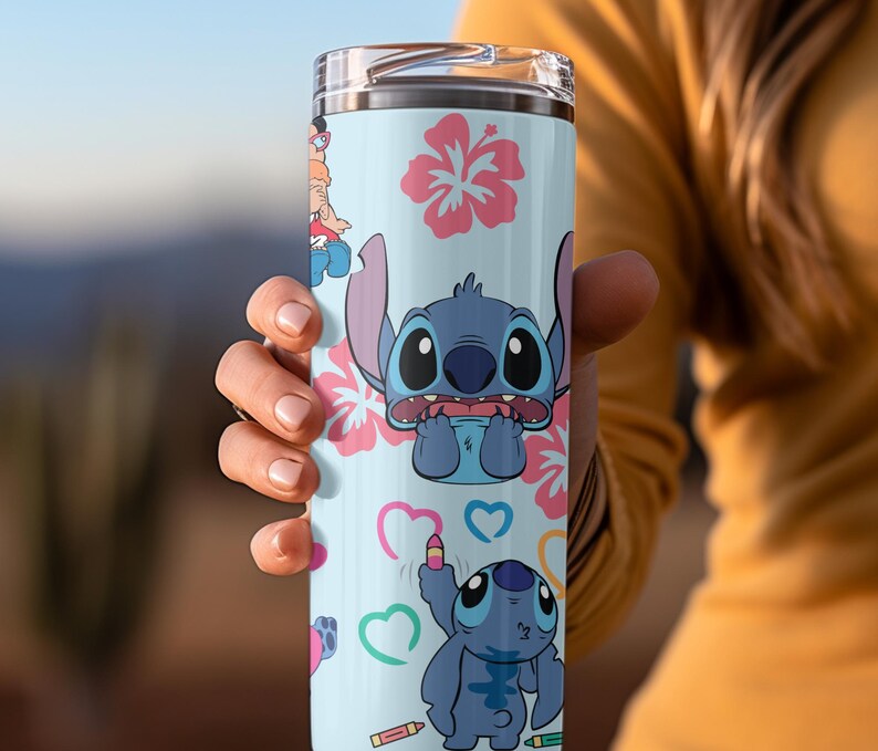 May include: A blue and white stainless steel tumbler with a design featuring Stitch from Lilo & Stitch. The design includes Stitch with hearts, flowers, and crayons.