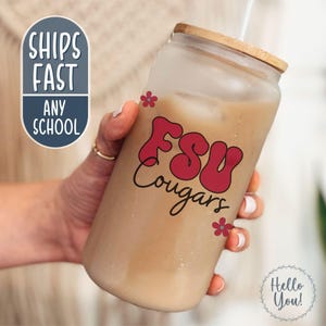 May include: A frosted glass tumbler with a wooden lid, filled with a light brown beverage and a straw. The tumbler features the text "FSU Cougars" in red, with small red flower accents. The words "Ships Fast Any School" are also visible.