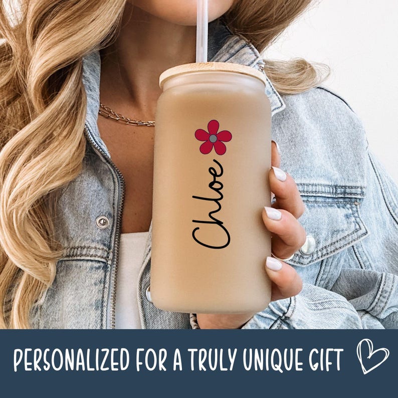 May include: A beige glass tumbler with a bamboo lid and a clear straw. The tumbler is decorated with a red and pink flower and the name "Chloe" in black script. The bottom of the image has the text "PERSONALIZED FOR A TRULY UNIQUE GIFT".
