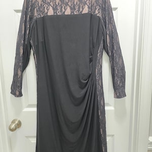 May include: A black knee-length dress featuring long sleeves and a yoke made of black floral lace over a nude-colored lining. The dress has a solid black front panel with gathered side detailing and a Chaps brand label at the inner neckline.