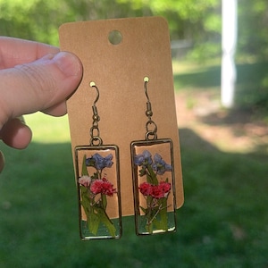 May include: A white ceramic mug with a black handle and the text "But First, Coffee" in a bold, black font. The mug is set against a blurred background, suggesting a cozy setting.