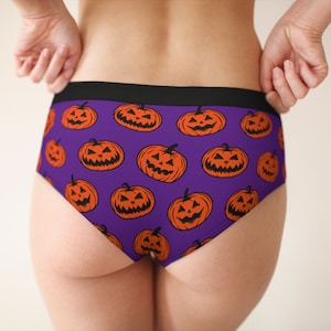 Puede incluir: Bóxer morado con un patrón repetido de caras de calabaza naranja.
