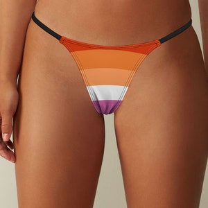 May include: A black string bikini bottom with a multi-colored striped pattern. The pattern features orange, peach, white, and purple stripes.