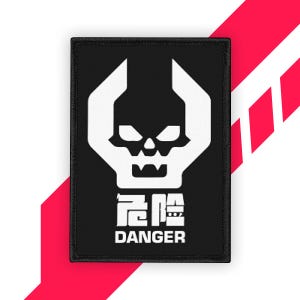 Może przedstawiać: Czarna prostokątna naszywka z białym wzorem czaszki z elementami przypominającymi klucz. Poniżej czaszki naszywka wyświetla słowo "DANGER" w języku angielskim, z chińskimi znakami powyżej. Naszywka jest obramowana na czarno.