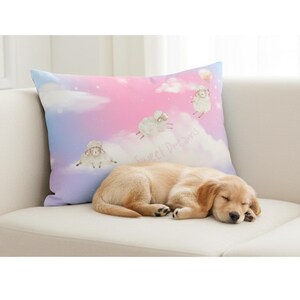 May include: A decorative pillow with a pastel sky design featuring cartoon sheep and the text "Sweet Dreams." A sleeping golden retriever puppy rests on a white sofa, next to the pillow.