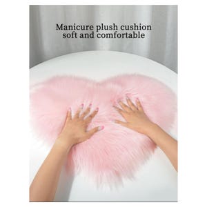 May include: A pink heart-shaped plush cushion. The cushion is soft and fluffy, and it is perfect for adding a touch of comfort to any room.