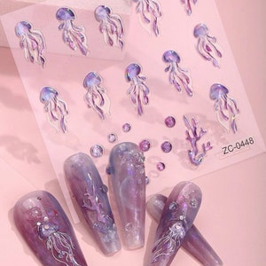 May include: A sheet of nail art stickers featuring purple and white jellyfish, coral, and iridescent dots. The stickers are on a pink background. The text "ZC-0448" is in the bottom right corner of the sheet.