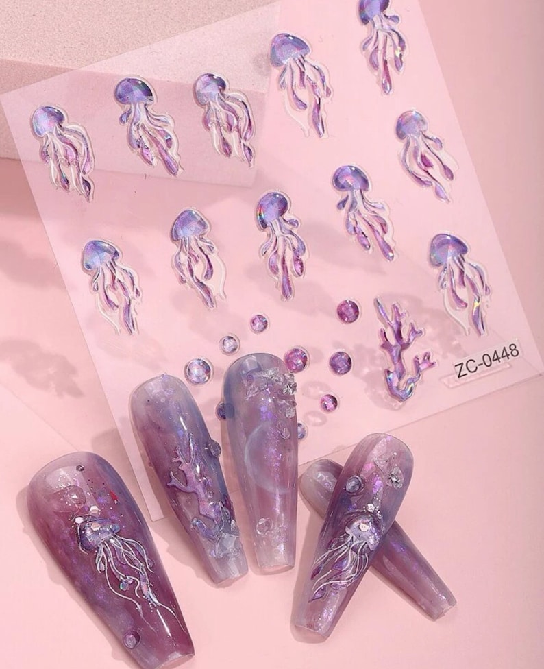 May include: A sheet of nail art stickers featuring purple and white jellyfish, coral, and iridescent dots. The stickers are on a pink background. The text "ZC-0448" is in the bottom right corner of the sheet.