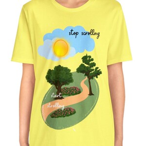 Può includere: Maglietta gialla con una grafica di un sentiero attraverso un parco con il testo "stop scrolling" e "start strolling" su uno sfondo verde.