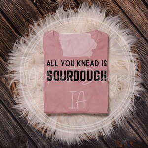 May include: A pink t-shirt with the text "All you knead is sourdough IA" printed in black.