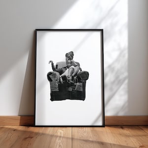 May include: Monochrome framed print showing two people seated in a patchwork armchair. The subjects are wearing head coverings and dark clothing. The print is leaning against a white wall on a wooden floor.