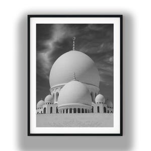 May include: A black and white framed wall art print featuring the architectural exterior of a mosque with multiple large domes. The central dome is the largest, topped with a crescent finial, surrounded by smaller domes and arched windows.
