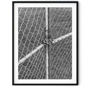 May include: A black and white photograph of a chain link fence with a metal chain wrapped around the fence posts.