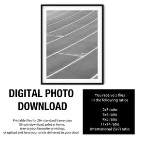 May include: A black and white digital print featuring a high-angle view of an athletic running track with white lane markings and the text 4x100 printed on the surface. The artwork is displayed within a thin black frame against a white background.
