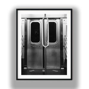 以下が含まれることがあります： モノクロ写真の地下鉄の車両ドア。ドアは閉まっており、中央に垂直の金属棒があります。「Do not hold doors」と「Do not lean on door」の文字がドアに表示されています。画像は黒いフレームで囲まれています。