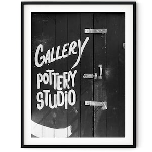 May include: Black and white photo of a wooden door with a sign that reads "Gallery Pottery Studio".