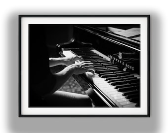 May include: A black and white framed print featuring a Steinway & Sons grand piano with keys being played. The high-contrast image captures the glossy finish of the instrument, the detailed keyboard, and the brand name clearly visible in white text.