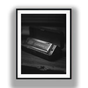 Könnte beinhalten: Schwarz-Weiß-Foto einer Mundharmonika in ihrem geöffneten Etui. Die Mundharmonika ist silberfarben mit dem Aufdruck "HARMONICA". Das Etui ist schwarz und rechteckig. Das Bild ist schwarz gerahmt.