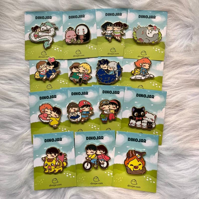 May include: A collection of 12 enamel pins featuring characters from popular animated films. The pins are colorful and feature a variety of characters, including Totoro, Kiki's Delivery Service, and Spirited Away. The pins are all set against a green background with the word "DINOJAR" printed on each card.
