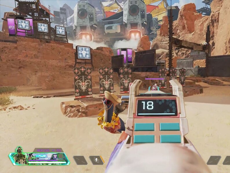 Peut inclure: Vue subjective d'une sc&egrave;ne de jeu vid&eacute;o. L'arme du joueur est au centre, affichant le chiffre 18 sur un &eacute;cran num&eacute;rique. L'environnement du jeu pr&eacute;sente des cibles, des structures futuristes et un paysage d&eacute;sertique. L'interface du jeu est visible en bas &agrave; gauche.