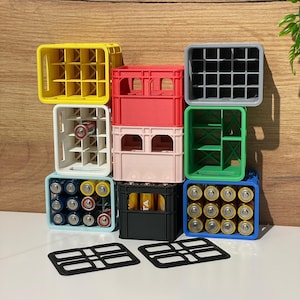 Könnte beinhalten: Ein Stapel bunter Plastikkisten, einige mit Batterien gefüllt, andere leer. Die Kisten sind pyramidenförmig angeordnet, wobei die oberste Kiste hellgrau ist. Die Kisten sind alle gleich groß und haben ein Gittermuster auf der Vorderseite.