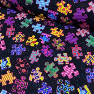 Puede incluir: Tela negra con un patrón repetido de coloridas piezas de rompecabezas. Las piezas del rompecabezas presentan varios diseños, incluyendo corazones, labios, estampado de leopardo y la palabra "COOL". Las piezas son en tonos de rosa, morado, amarillo, azul y verde.
