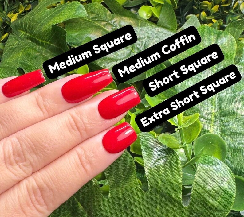 K&ouml;nnte beinhalten: Eine Hand mit rotem Nagellack, die verschiedene Nagelformen zeigt: Medium Square, Medium Coffin, Short Square und Extra Short Square. Die N&auml;gel sind leuchtend rot, vor einem Hintergrund aus gr&uuml;nem Laub.
