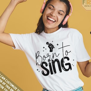 May include: A white t-shirt with a black graphic design that says "Born to Sing" with a microphone and hand holding the microphone. The design also includes small stars.