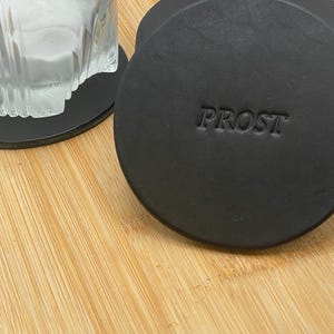 Könnte beinhalten: Ein Set aus drei Keramikbechern mit gesprenkelter, matter Oberfläche. Die Becher sind in Creme-, Hellgrau- und Dunkelgrautönen gehalten. Jeder Becher hat ein schlichtes, minimalistisches Design, ideal für Kaffee oder Tee.