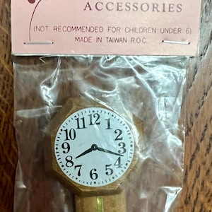May include: Miniature clock accessory with a light brown wooden frame and a white clock face. The clock face has black numbers and hands. The packaging reads "MINIATURE ACCESSORIES" and "MADE IN TAIWAN R.O.C."