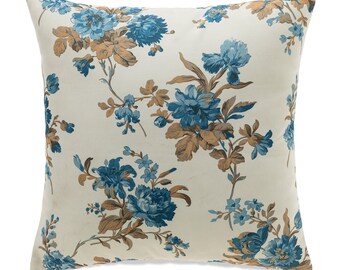 May include: A white pillow with a floral pattern in shades of blue and brown. The pillow has a zipper closure.