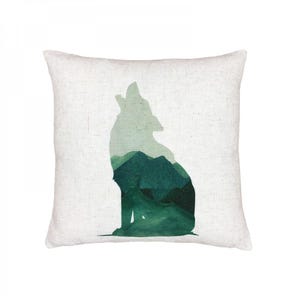 May include: A throw pillow with a green watercolor silhouette of a wolf howling at the moon. The wolf is outlined in a lighter shade of green, and the inside of the wolf is filled with a darker shade of green. The background of the pillow is a light beige.