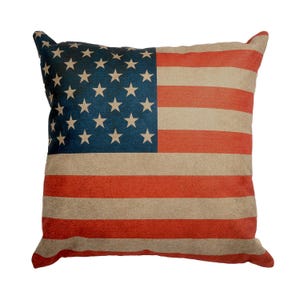 Può includere: Un cuscino decorativo con un design di bandiera americana vintage. Il cuscino è realizzato in un tessuto morbido e testurizzato e presenta un aspetto sbiadito e usurato.