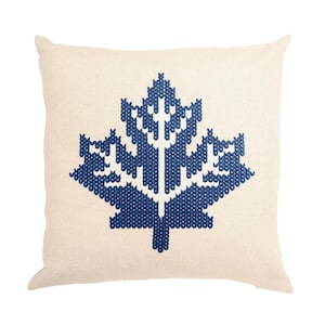Peut inclure: Un coussin blanc avec un motif de feuille d'érable brodé en bleu.