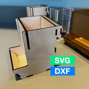 May include: A wooden dice tower with a compartment for dice. The tower is made of light wood with dark brown accents. The tower is sitting on a light brown surface. The image also includes the text "SVG" and "DXF".